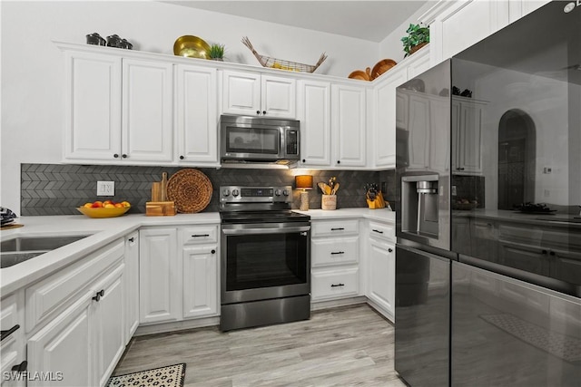 3007 8th St W, Lehigh Acres, FL 33971 - kitchen with stainless steel appliances, white cabinetry, and backsplash