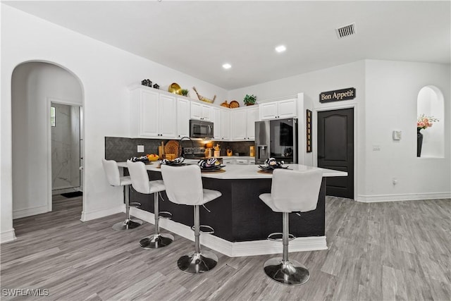 3007 8th St W, Lehigh Acres, FL 33971 - kitchen featuring stainless steel refrigerator with ice dispenser, arched walkways, a peninsula, light wood-style flooring, and a kitchen bar