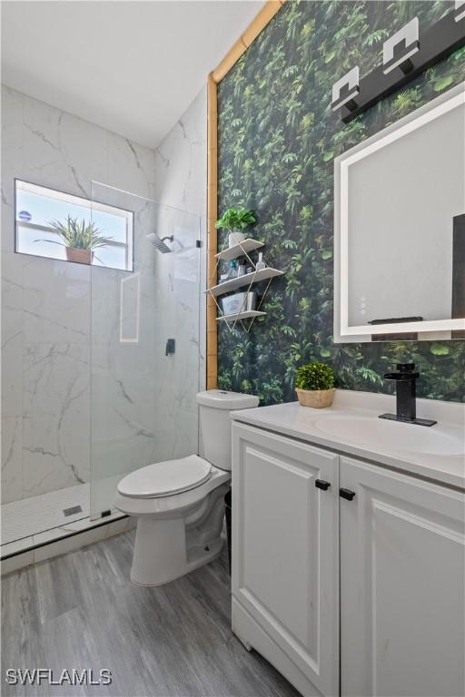 3007 8th St W, Lehigh Acres, FL 33971 - full bath featuring wallpapered walls, a marble finish shower, toilet, vanity, and wood finished floors