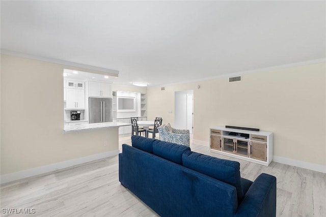 living area with baseboards, light wood finished floors, and visible vents