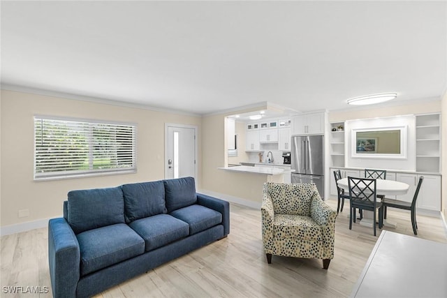 living room featuring light wood-style floors, baseboards, and ornamental molding
