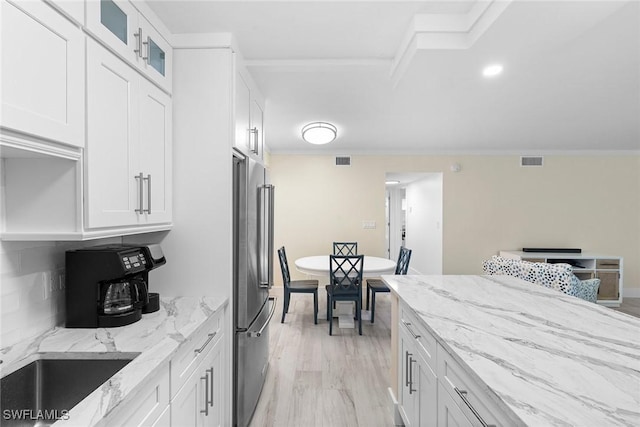 kitchen with white cabinets, high quality fridge, visible vents, and glass insert cabinets