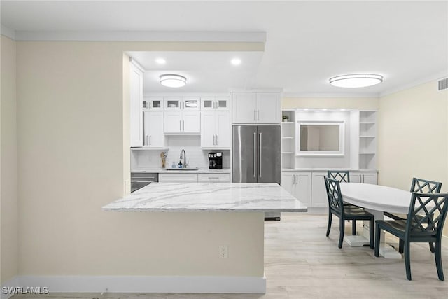 kitchen with open shelves, white cabinets, high end fridge, and a sink