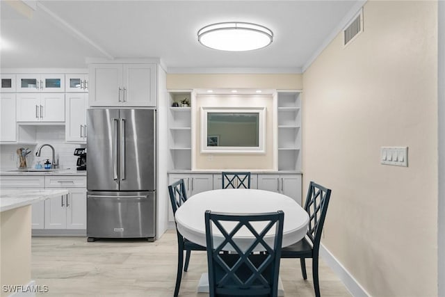 kitchen with high quality fridge, a sink, visible vents, and light wood-type flooring