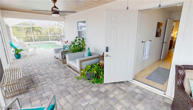view of patio / terrace featuring a ceiling fan, an outdoor pool, and glass enclosure