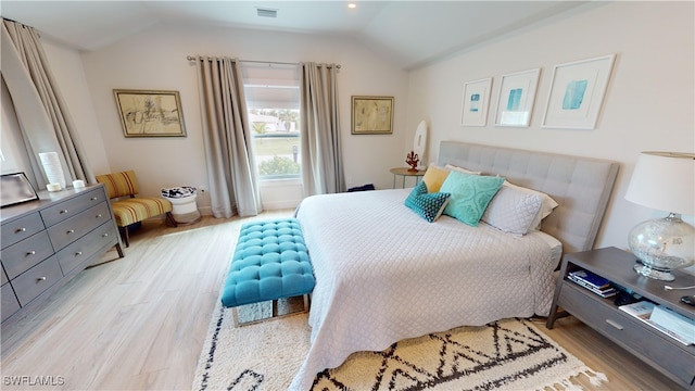 bedroom with light wood-style flooring, vaulted ceiling, and baseboards