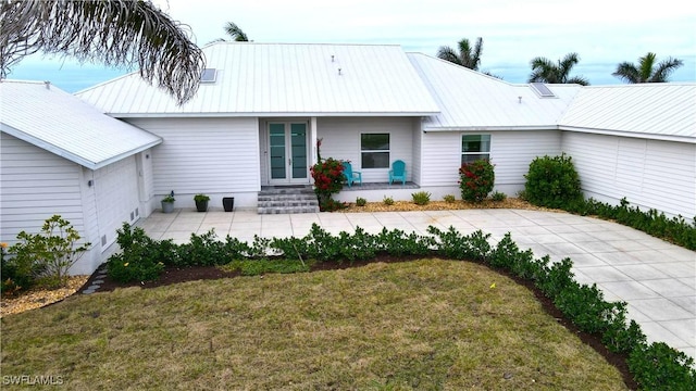 view of front of house featuring a front yard, metal roof, and french doors