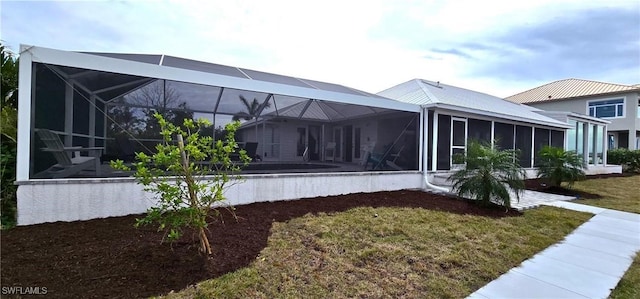 view of side of home with a lawn and glass enclosure