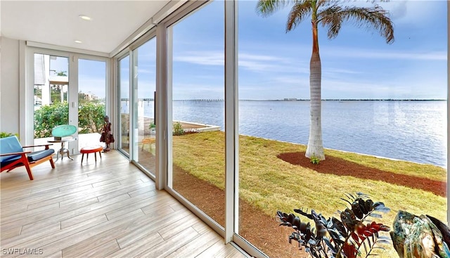 sunroom / solarium featuring a water view, floor to ceiling windows, wood finished floors, and recessed lighting