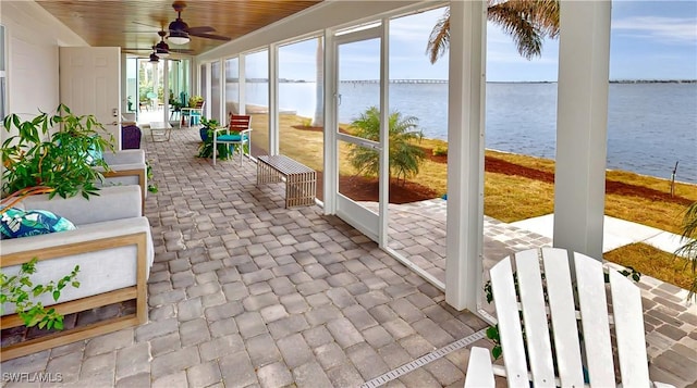 sunroom featuring a water view and ceiling fan