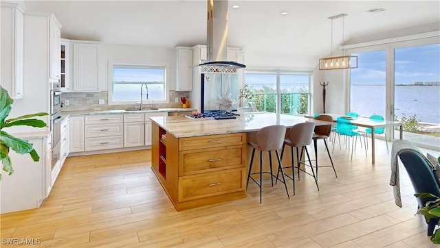 kitchen featuring a sink, vaulted ceiling, gas cooktop, decorative backsplash, and white cabinets