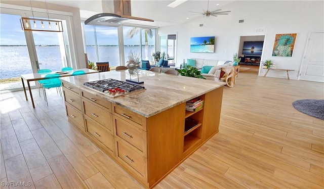 kitchen featuring stainless steel gas cooktop, light wood-style floors, a ceiling fan, open shelves, and light stone counters