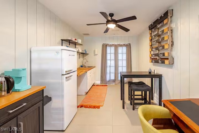 kitchen with open shelves, a sink, freestanding refrigerator, dark brown cabinetry, and a ceiling fan
