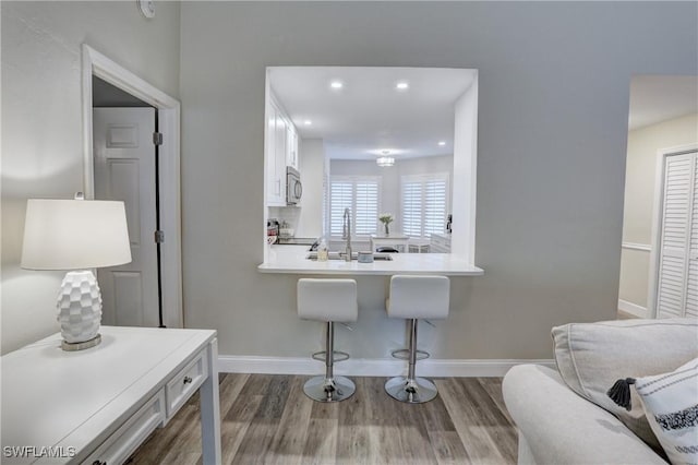 interior space featuring white cabinetry, dark wood-style flooring, a sink, and a breakfast bar
