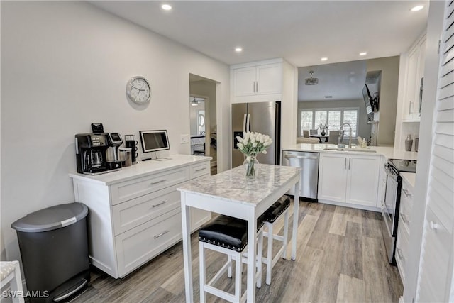 kitchen featuring a sink, light wood-style floors, stainless steel appliances, light countertops, and white cabinets