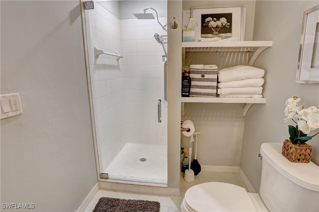 bathroom featuring a shower stall, toilet, and baseboards