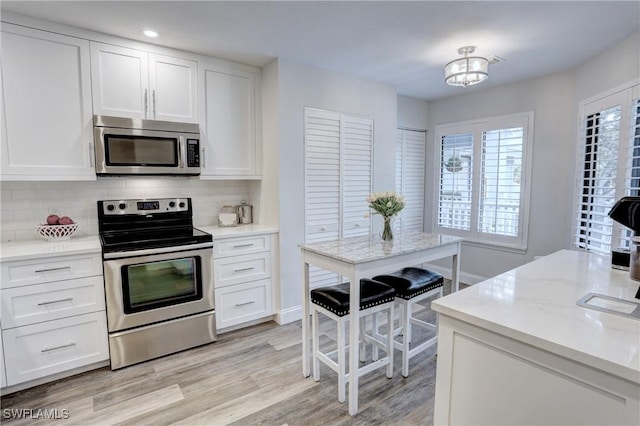 kitchen with backsplash, white cabinetry, and appliances with stainless steel finishes