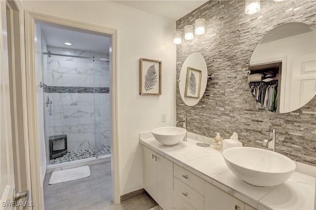 bathroom with backsplash, a sink, a shower stall, and double vanity