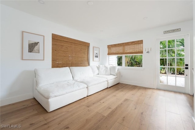 living area with baseboards, light wood-style floors, and plenty of natural light