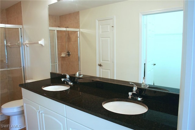 full bathroom featuring double vanity, a sink, a stall shower, and toilet