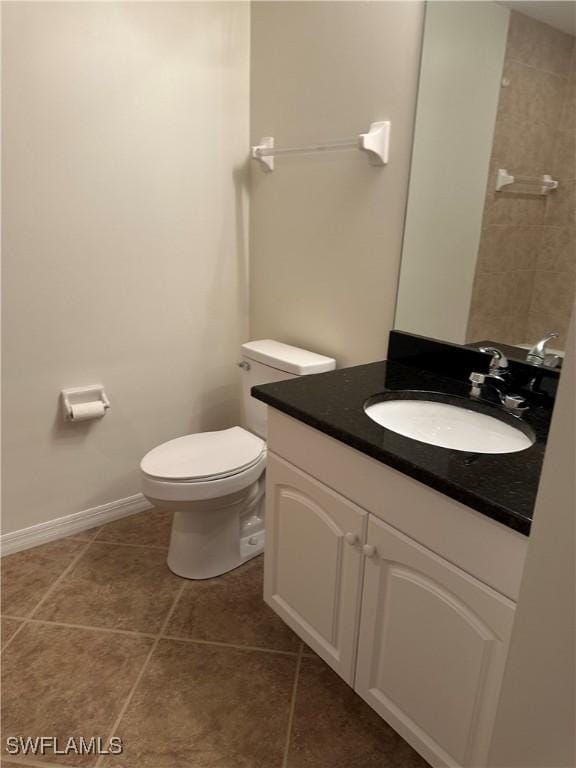 bathroom featuring vanity, tile patterned flooring, baseboards, and toilet