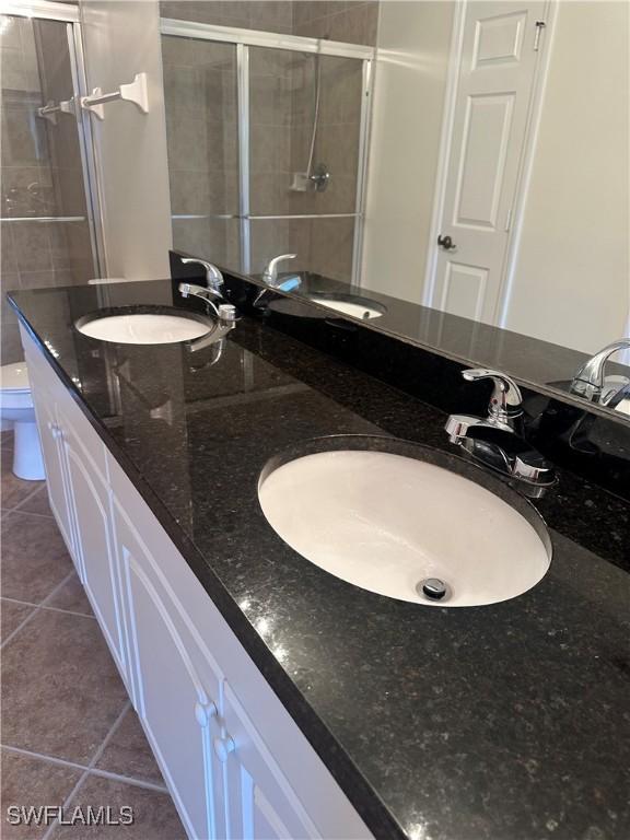 bathroom with tile patterned flooring, a sink, and a shower stall