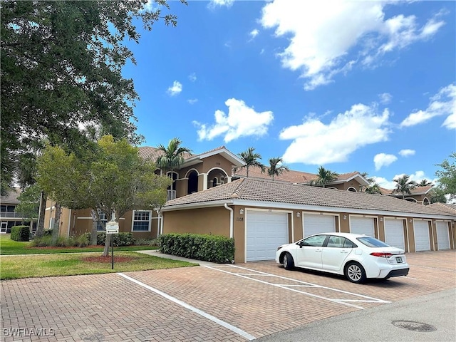 view of front facade featuring community garages, a tile roof, and stucco siding