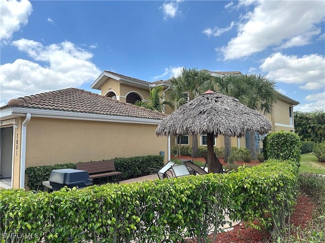 rear view of house with stucco siding and a tile roof