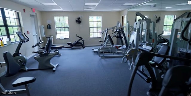 exercise room with baseboards and a paneled ceiling