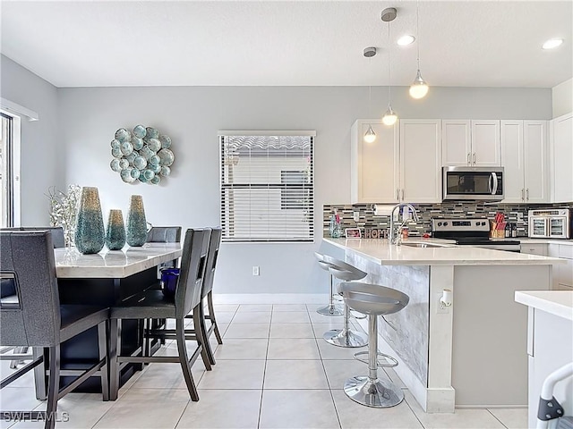 kitchen featuring stainless steel appliances, a sink, backsplash, white cabinetry, and light countertops