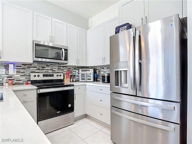 kitchen featuring stainless steel appliances, light countertops, decorative backsplash, and light tile patterned flooring
