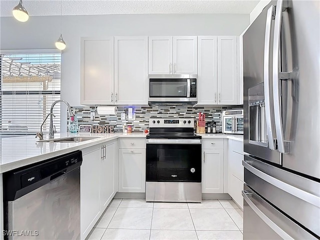 kitchen featuring stainless steel appliances, a sink, backsplash, and light tile patterned floors