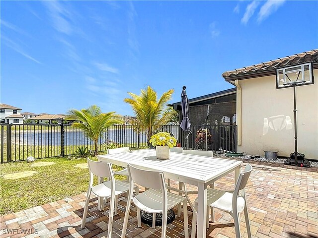 view of patio / terrace with a fenced backyard, outdoor dining area, and a water view