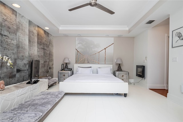 bedroom featuring a tray ceiling, a fireplace, visible vents, and recessed lighting