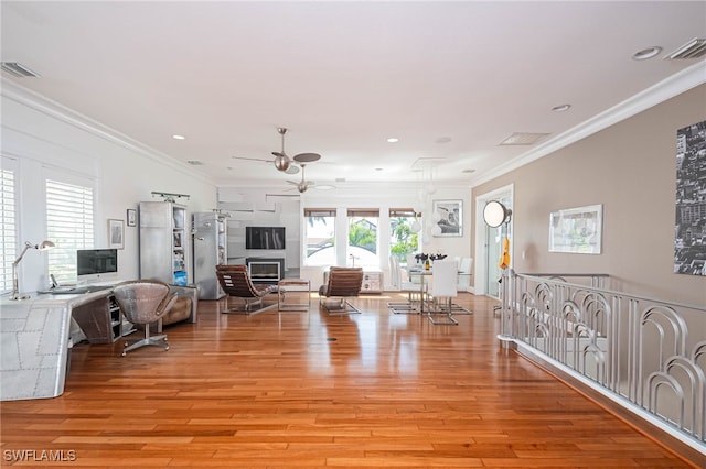 living area featuring a ceiling fan, crown molding, light wood finished floors, and visible vents