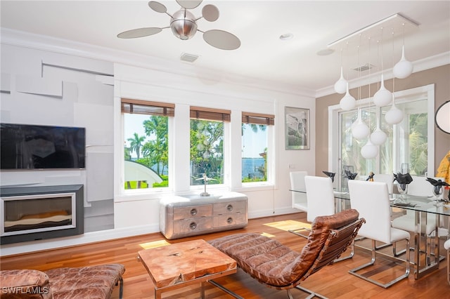 living area with baseboards, visible vents, crown molding, and wood finished floors