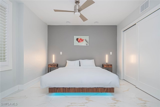 bedroom featuring a closet, marble finish floor, visible vents, a ceiling fan, and baseboards