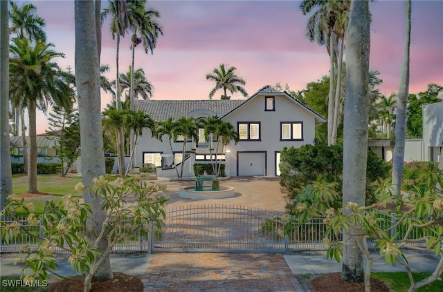 view of front of property with decorative driveway, a garage, stucco siding, a tile roof, and a gate