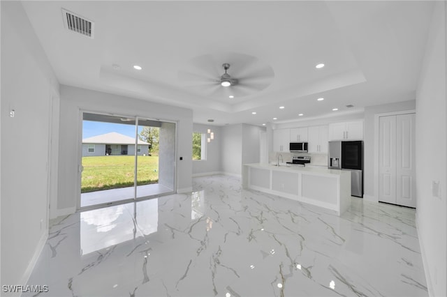 2932 18th St SW, Lehigh Acres, FL 33976 - unfurnished living room featuring a raised ceiling, recessed lighting, light marble finish floors, a sink, and baseboards