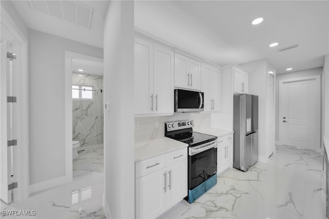 2932 18th St SW, Lehigh Acres, FL 33976 - kitchen with stainless steel appliances, light marble finish flooring, recessed lighting, and white cabinetry