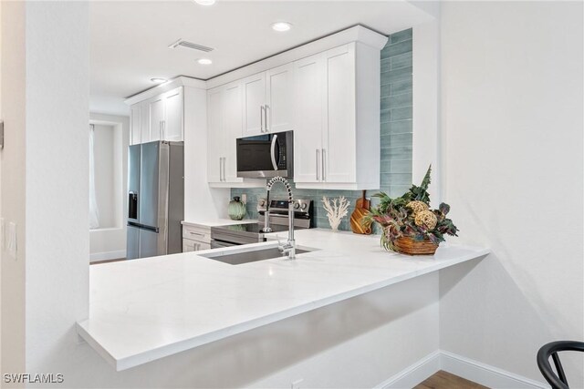 kitchen featuring visible vents, stainless steel appliances, white cabinets, and light countertops