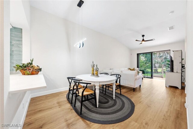 dining room with ceiling fan, visible vents, baseboards, light wood-type flooring, and vaulted ceiling