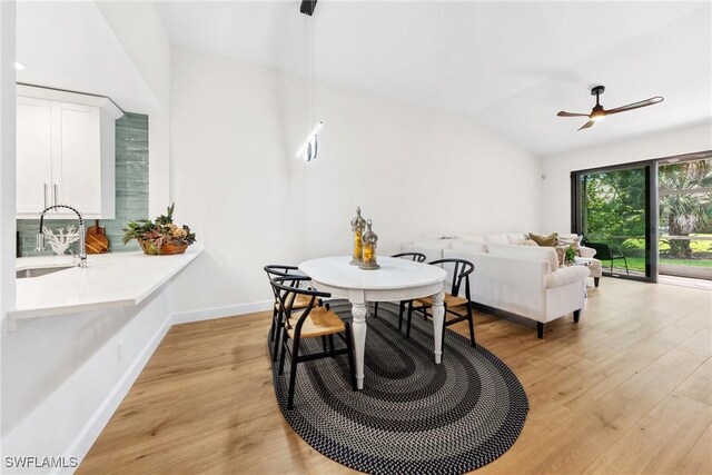 dining space featuring baseboards, light wood-type flooring, ceiling fan, and lofted ceiling
