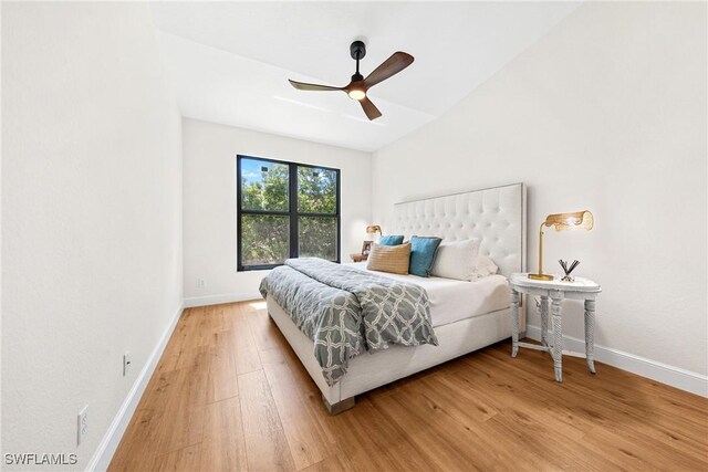 bedroom featuring baseboards, ceiling fan, light wood-style floors, and lofted ceiling