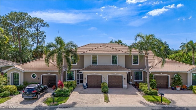 mediterranean / spanish house featuring a tile roof, driveway, and stucco siding