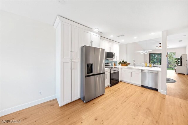 kitchen with white cabinets, stainless steel appliances, light countertops, and light wood-style flooring