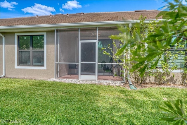 back of property featuring a lawn, stucco siding, and a sunroom