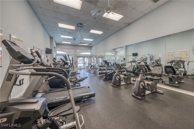 gym with a high ceiling, a paneled ceiling, and visible vents