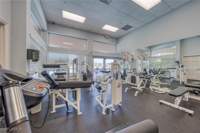 workout area with a towering ceiling and a paneled ceiling