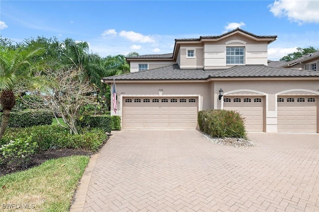 view of property with an attached garage, decorative driveway, and stucco siding